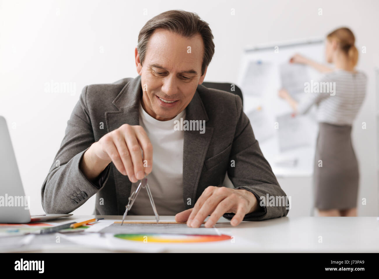 Positive engineer using compasses while drawing Stock Photo - Alamy