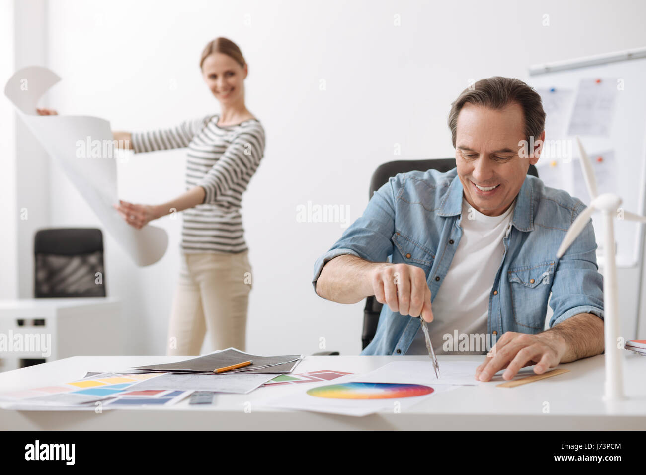 Cheerful engineer drawing with compasses Stock Photo - Alamy