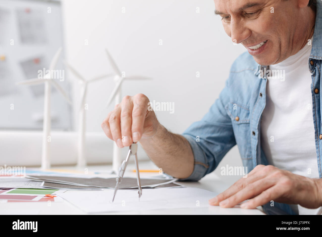 Cheerful skillful engineer drawing with compasses Stock Photo - Alamy