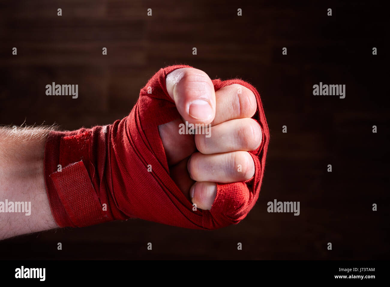 Close up image of fist of a boxer with red bandage against brown