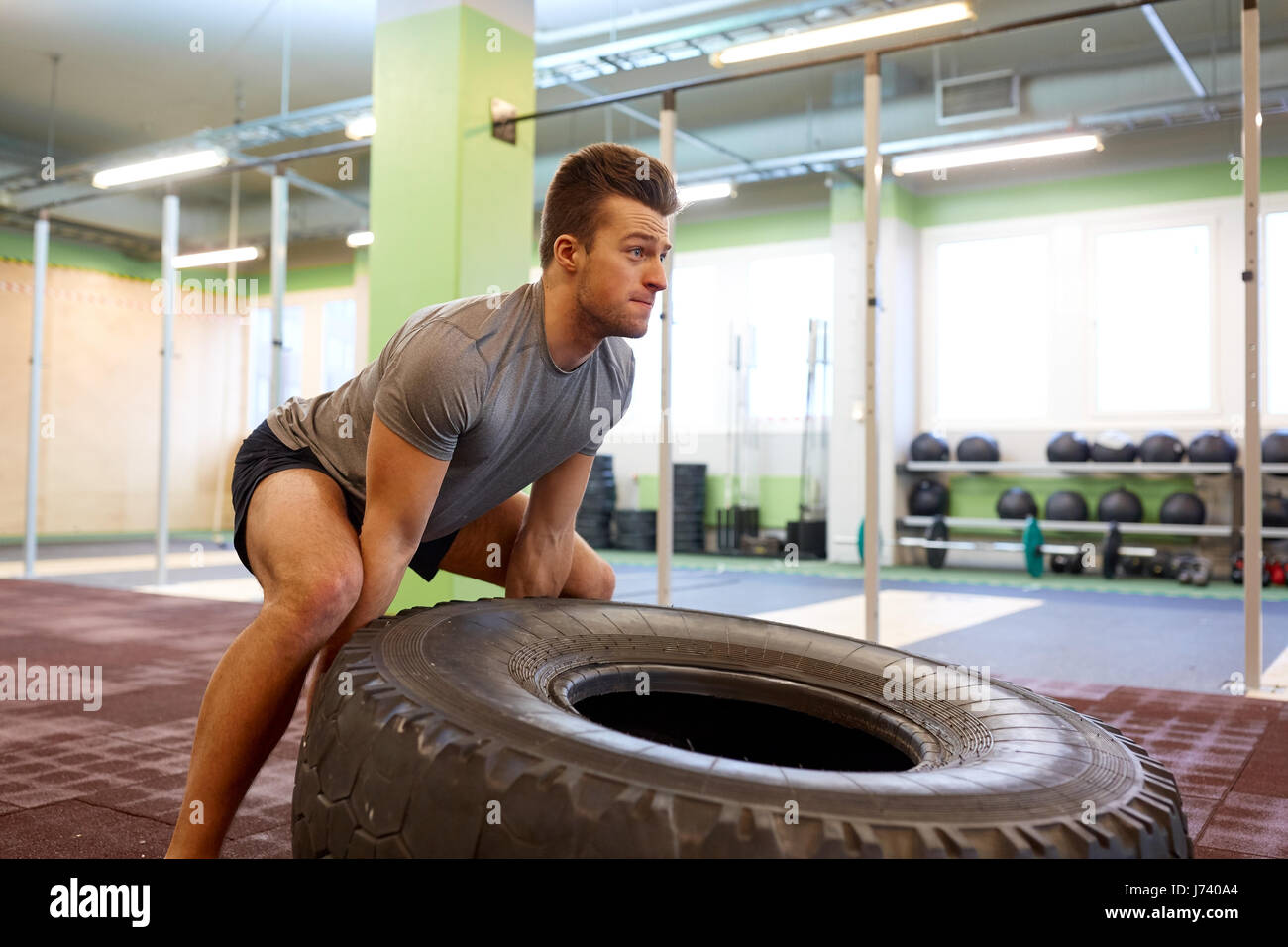 man doing strongman tire flip training in gym Stock Photo