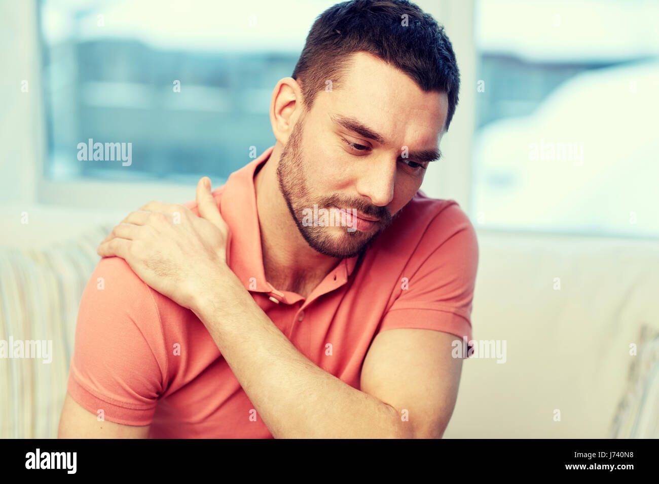 unhappy man suffering from neck pain at home Stock Photo - Alamy