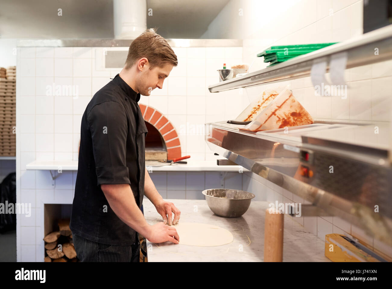 chef preparing pizza dough in kitchen at pizzeria Stock Photo