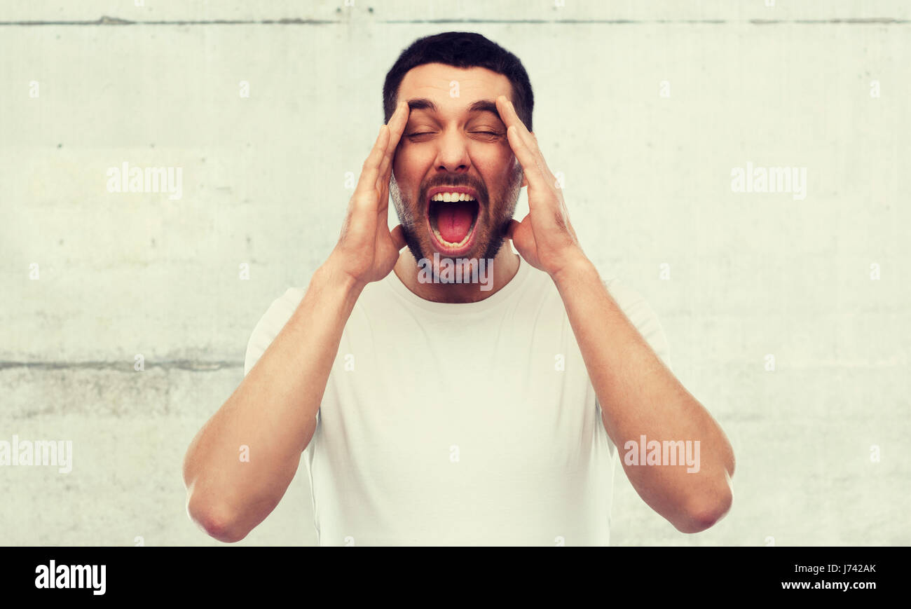 crazy shouting man in t-shirt over gray wall Stock Photo