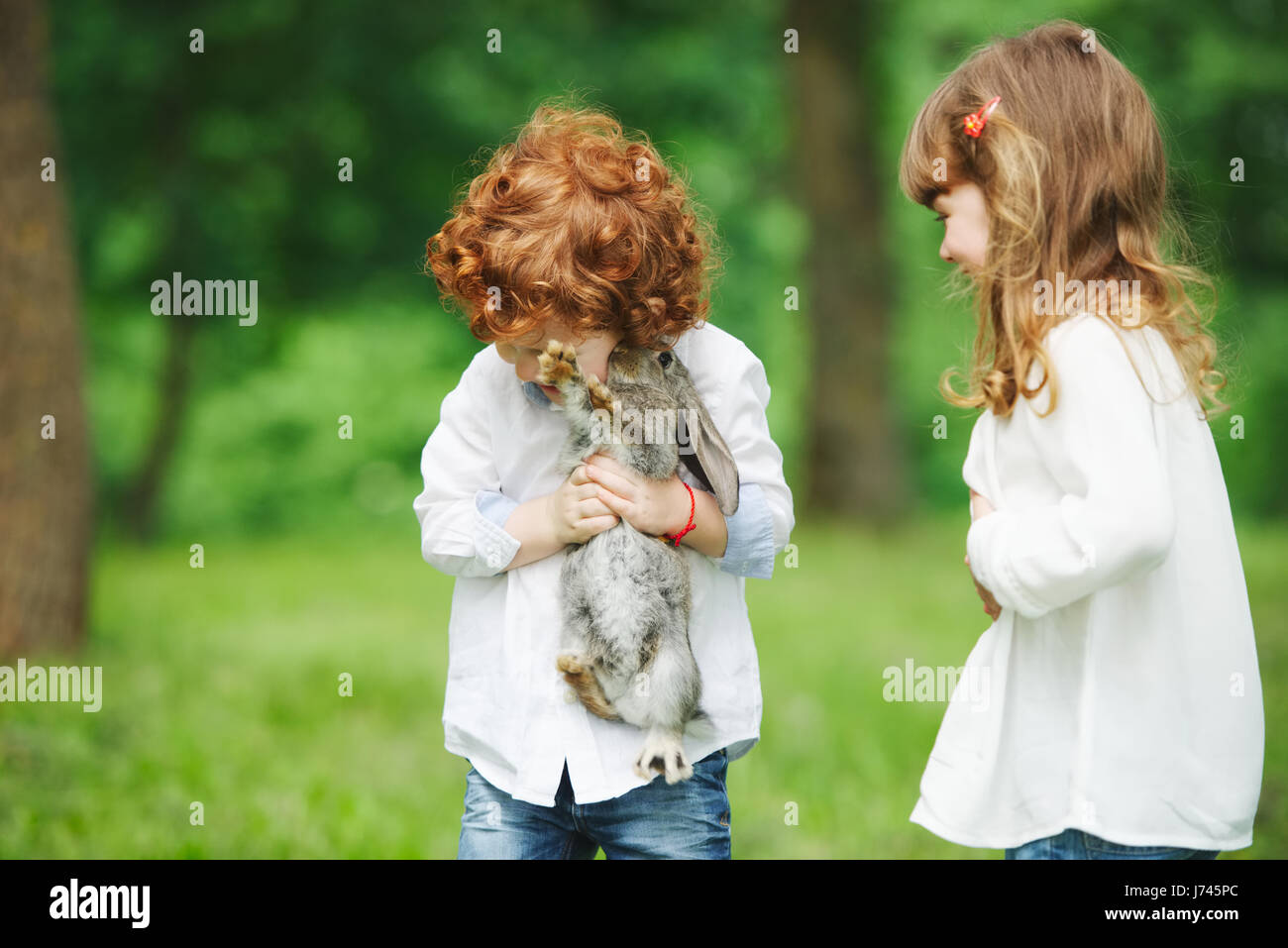 little boy and girl playing with rabbit Stock Photo