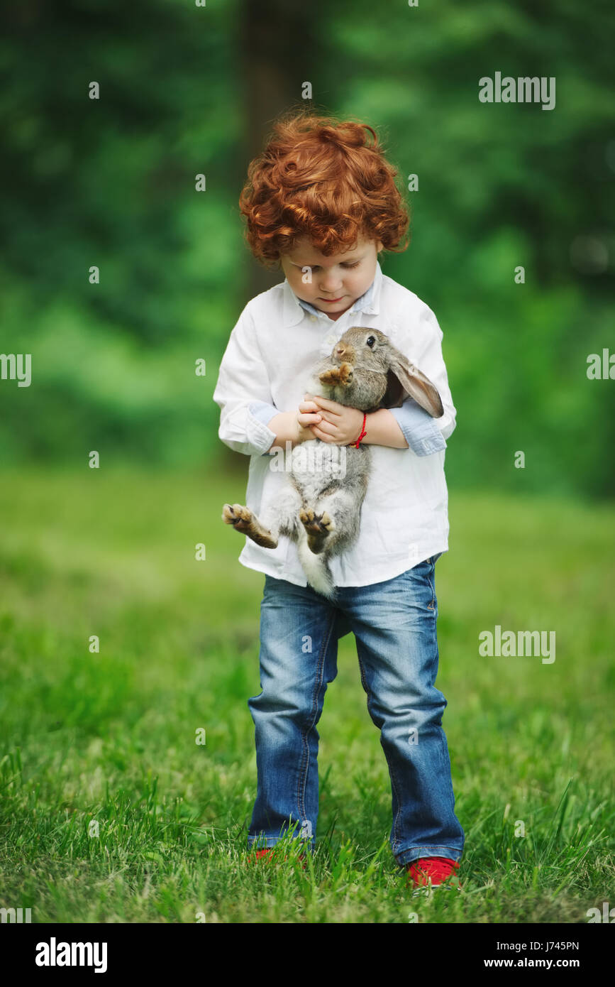 little boy with rabbit on grass Stock Photo