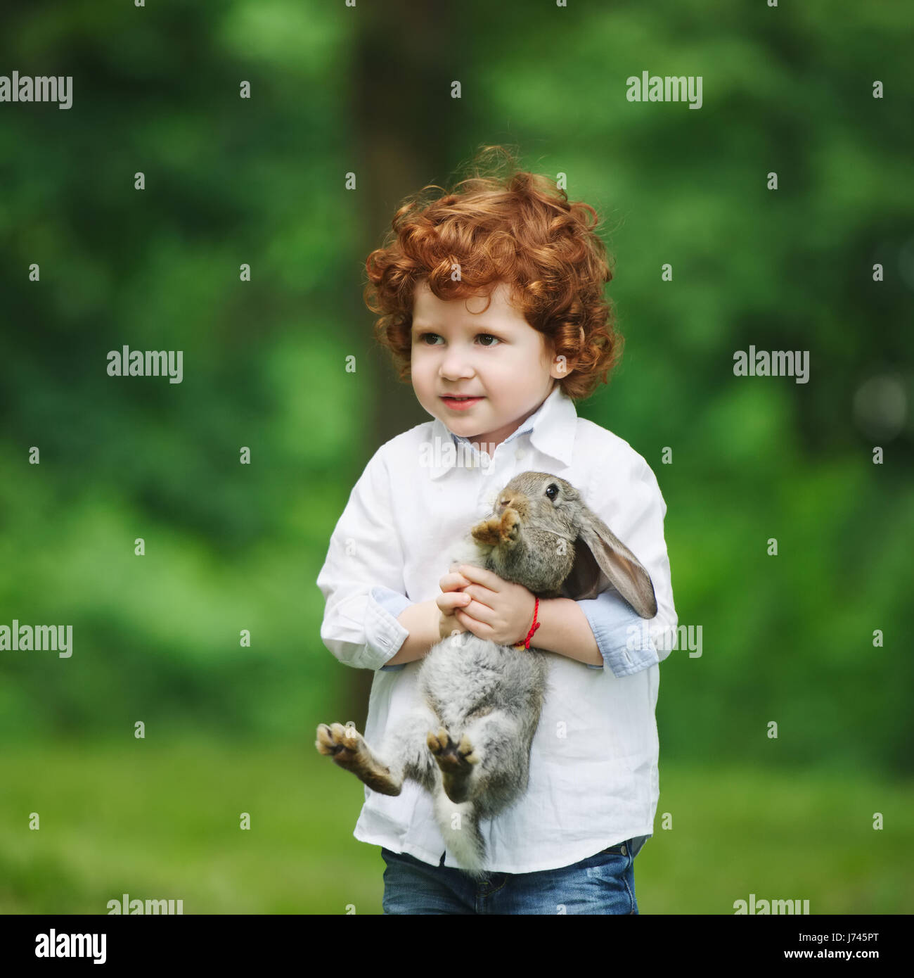 little boy with rabbit on grass Stock Photo