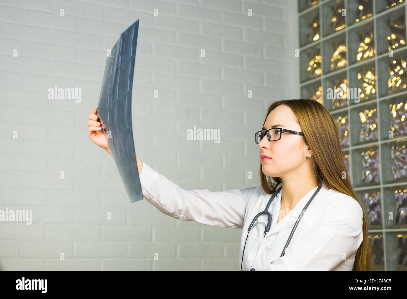 Portrait of intellectual woman healthcare personnel with white labcoat, looking at full body x-ray radiographic image, hospital clinic background. Radiology department Stock Photo