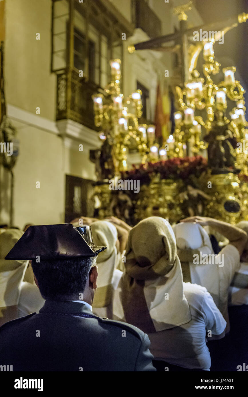 Member of the police corp Guardia Civil with their typical hat (tricornio) watching the image of Christ with a group of costaleros waiting for their t Stock Photo