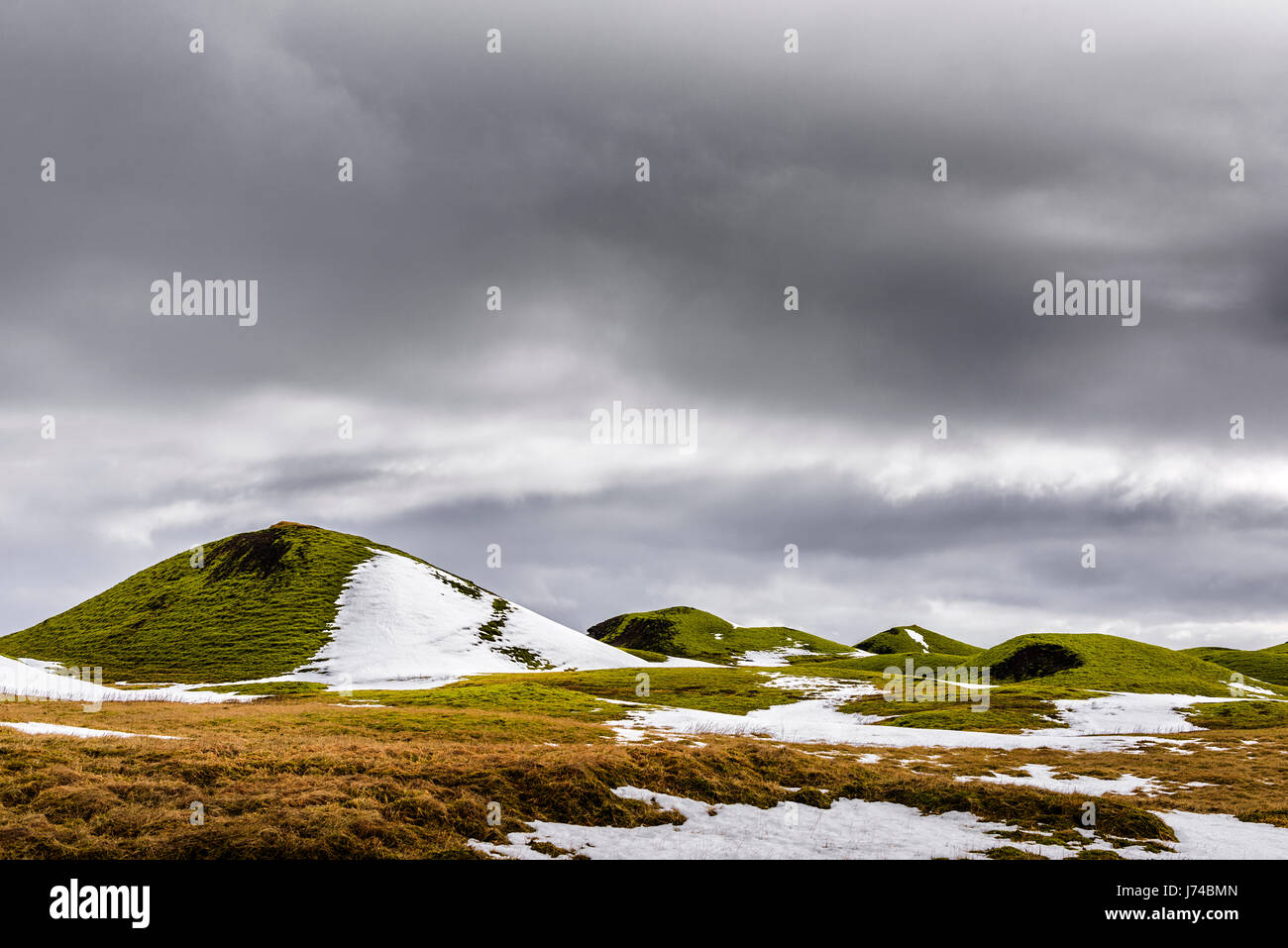 When the winter snow melts the green grass grows on the low hills of Iceland. Stock Photo