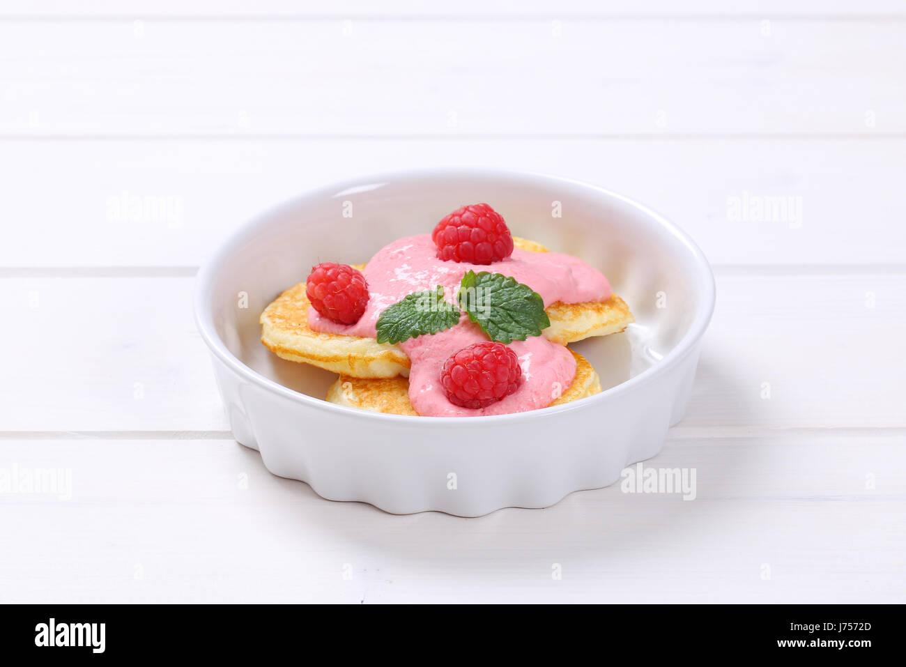 bowl of american pancakes with pink yogurt and fresh raspberries on white wooden background Stock Photo