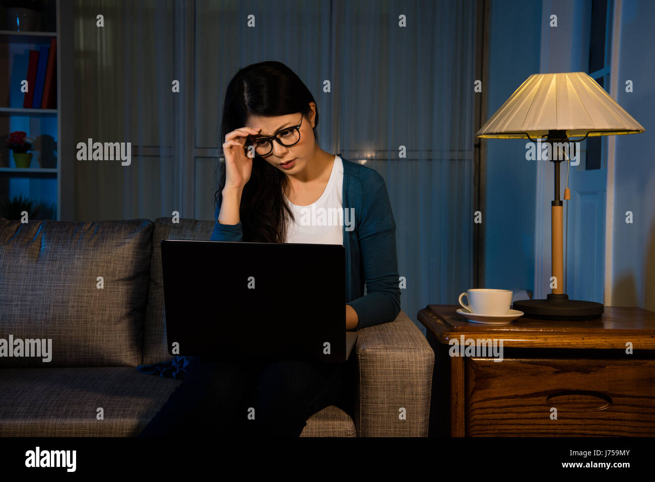 asian effort woman working in the office resting room late at night and touching her forehead, she having painful with headache, stress and overwork c Stock Photo