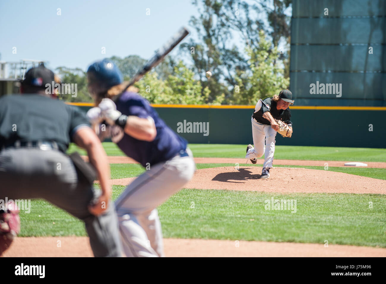 Baseball pitcher following through to pitch to left handed batter Stock