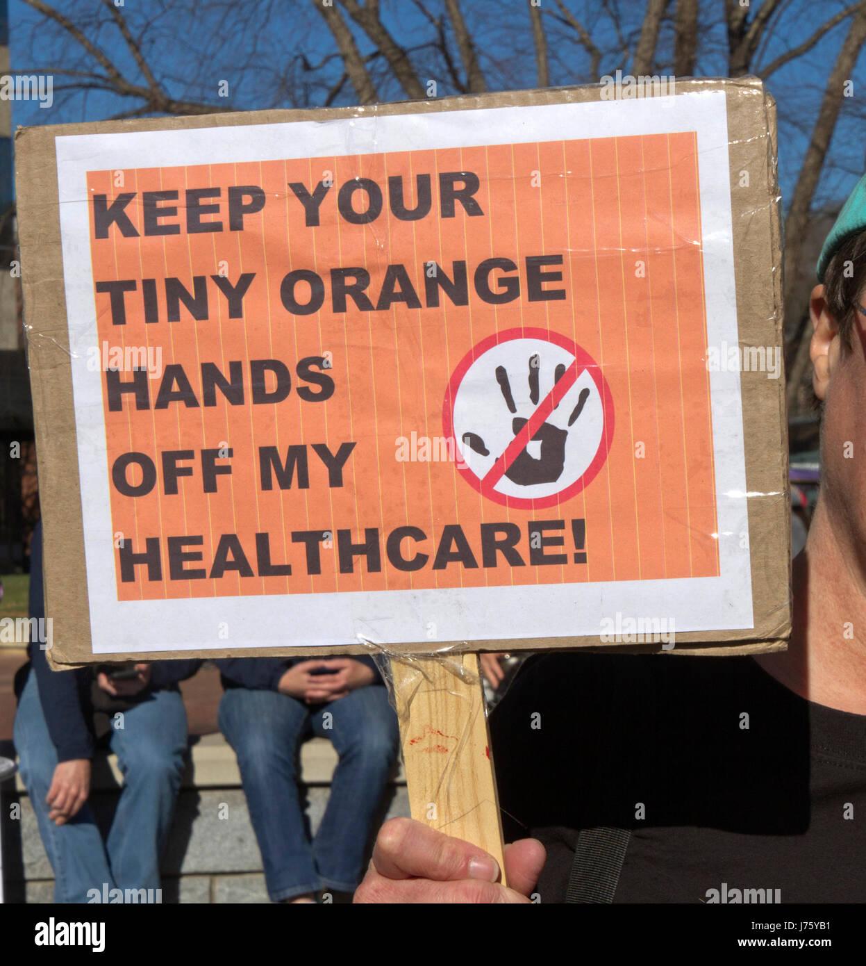 Asheville, North Carolina, USA - February 25, 2017:  A young man holds a sign at a crowded Affordable Care Act demonstration that says 'Keep Your Tiny Stock Photo