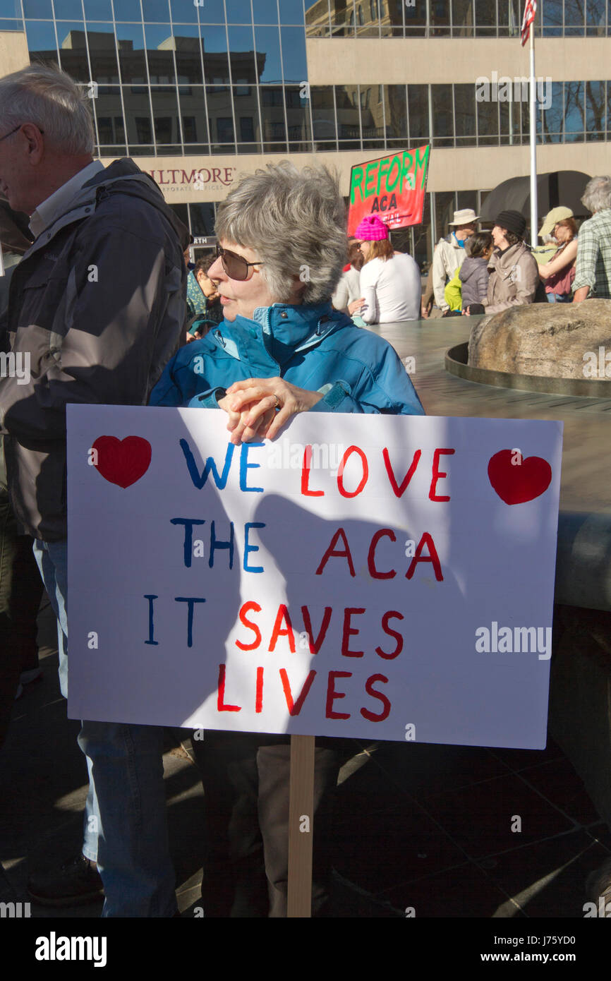 Asheville, North Carolina, USA - February 25, 2017:  A woman holds a sign at a crowded Affordable Care Act demonstration that says 'We Love the ACA, I Stock Photo