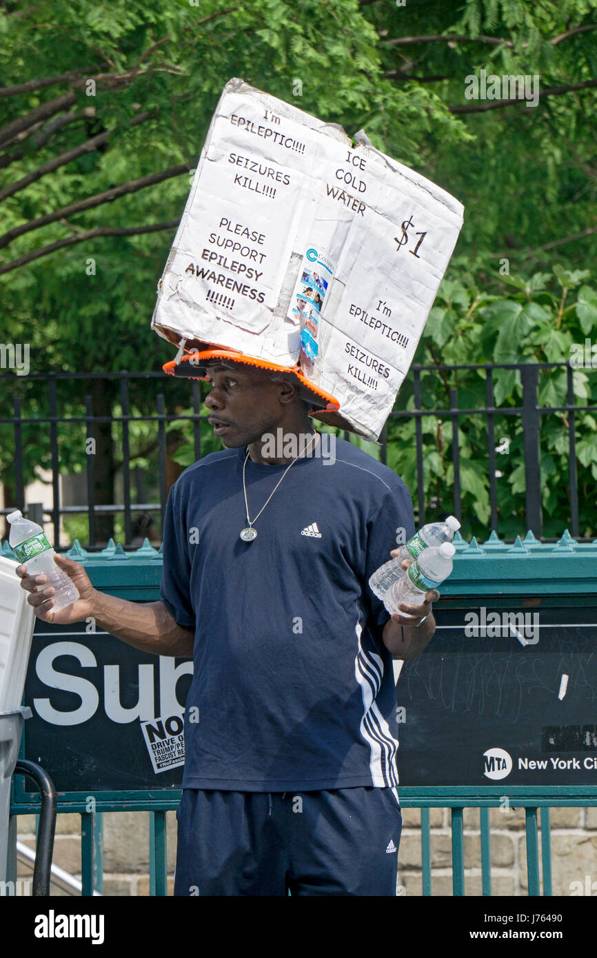 An African American man with epilepsy selling bottles of water with a homemade sign announcing his condition. In Union Square in Manhattan, NYC. Stock Photo