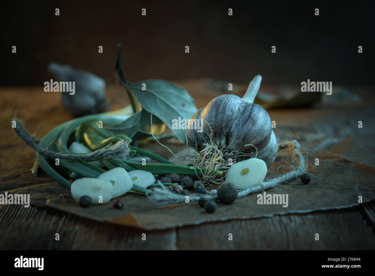 Head garlic, garlic cloves, Bay leaves on a wooden Board on a dark background Stock Photo