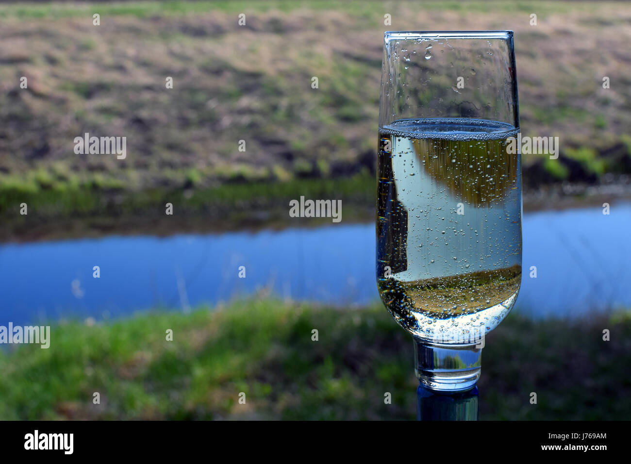 Glass of sparkling wine outdoors. Focus on foreground. Stock Photo