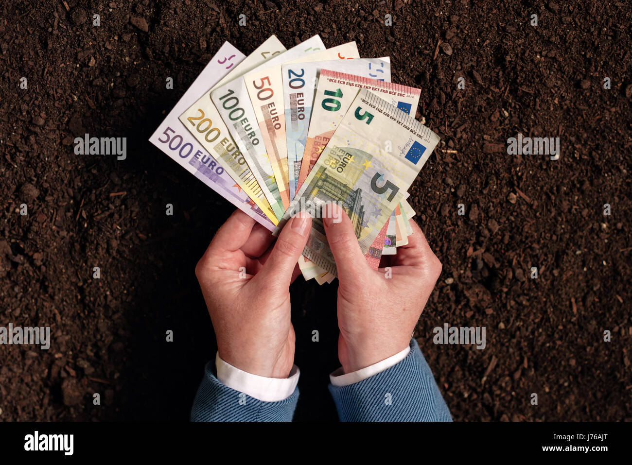 Bank loan for agricultural activity in euro banknotes, businesswoman in elegant business suit with european currency cash money over fertile soil Stock Photo