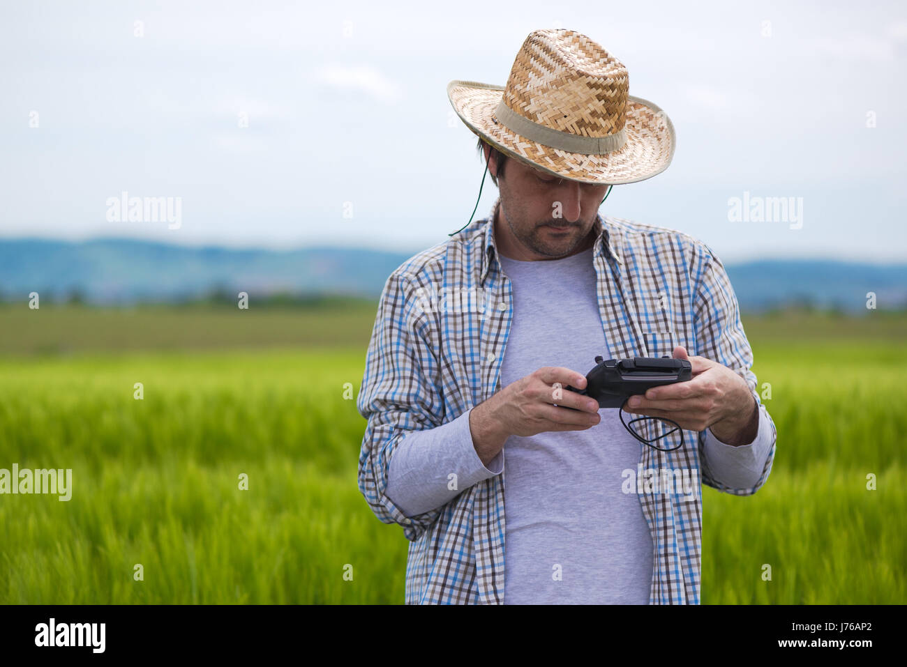 Smart farming concept, farmer using drone remote controller to navigate aircraft in cultivated field and examine crops Stock Photo