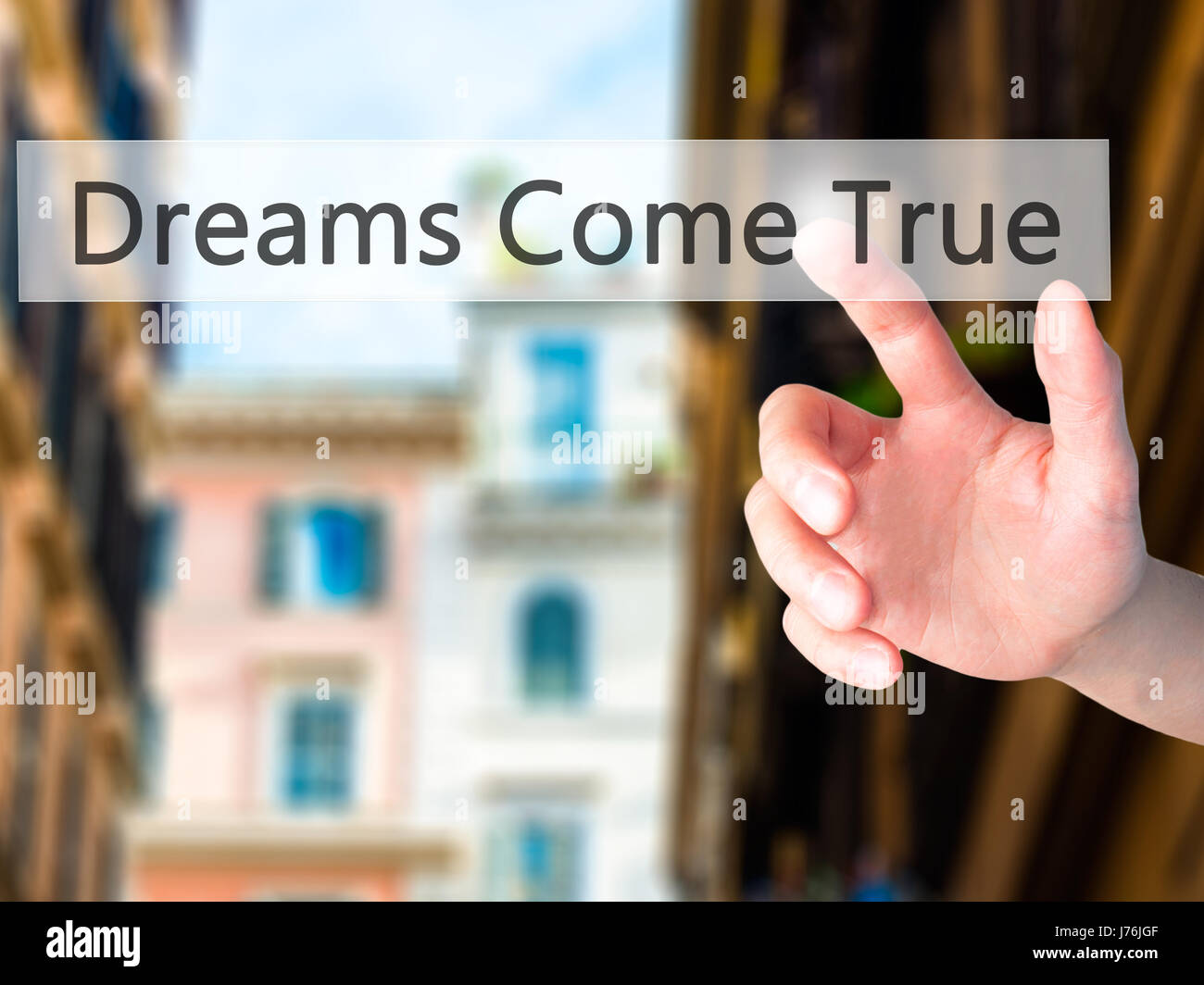 Dreams Come True - Hand pressing a button on blurred background concept . Business, technology, internet concept. Stock Photo Stock Photo