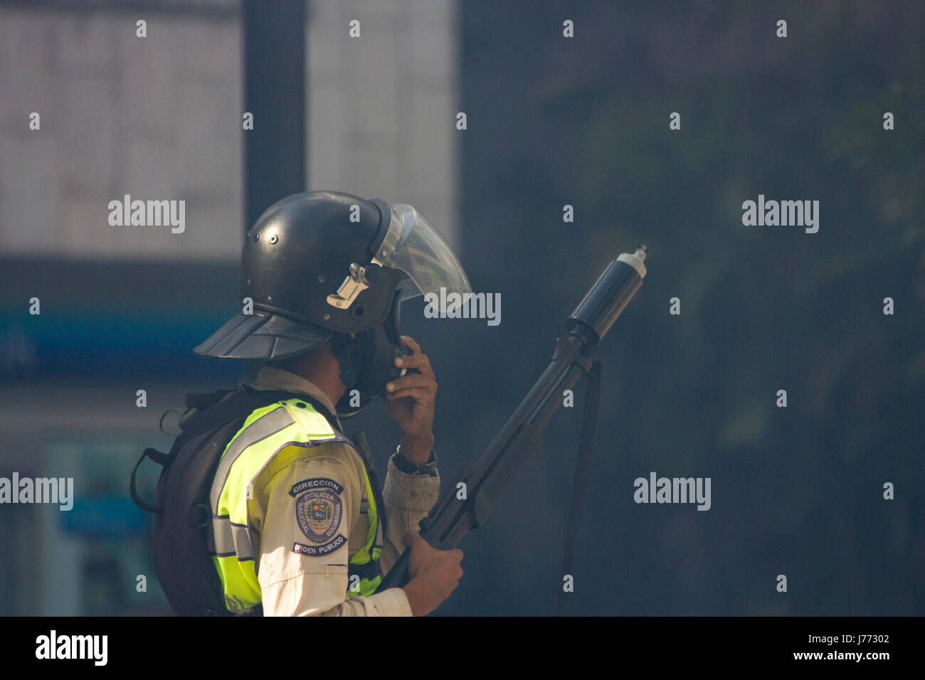 A police officer holds a shotgun with a tear gas canister during a protest against the government of Nicolas Maduro in Caracas. Stock Photo
