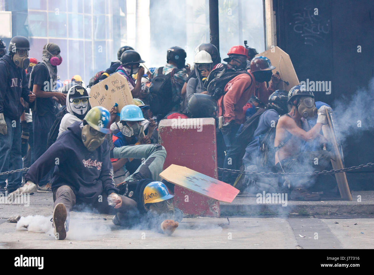 Demonstrators tries to catch a tear gas canister fired by the police during a protest against the government of Nicolas Maduro in Caracas. Stock Photo