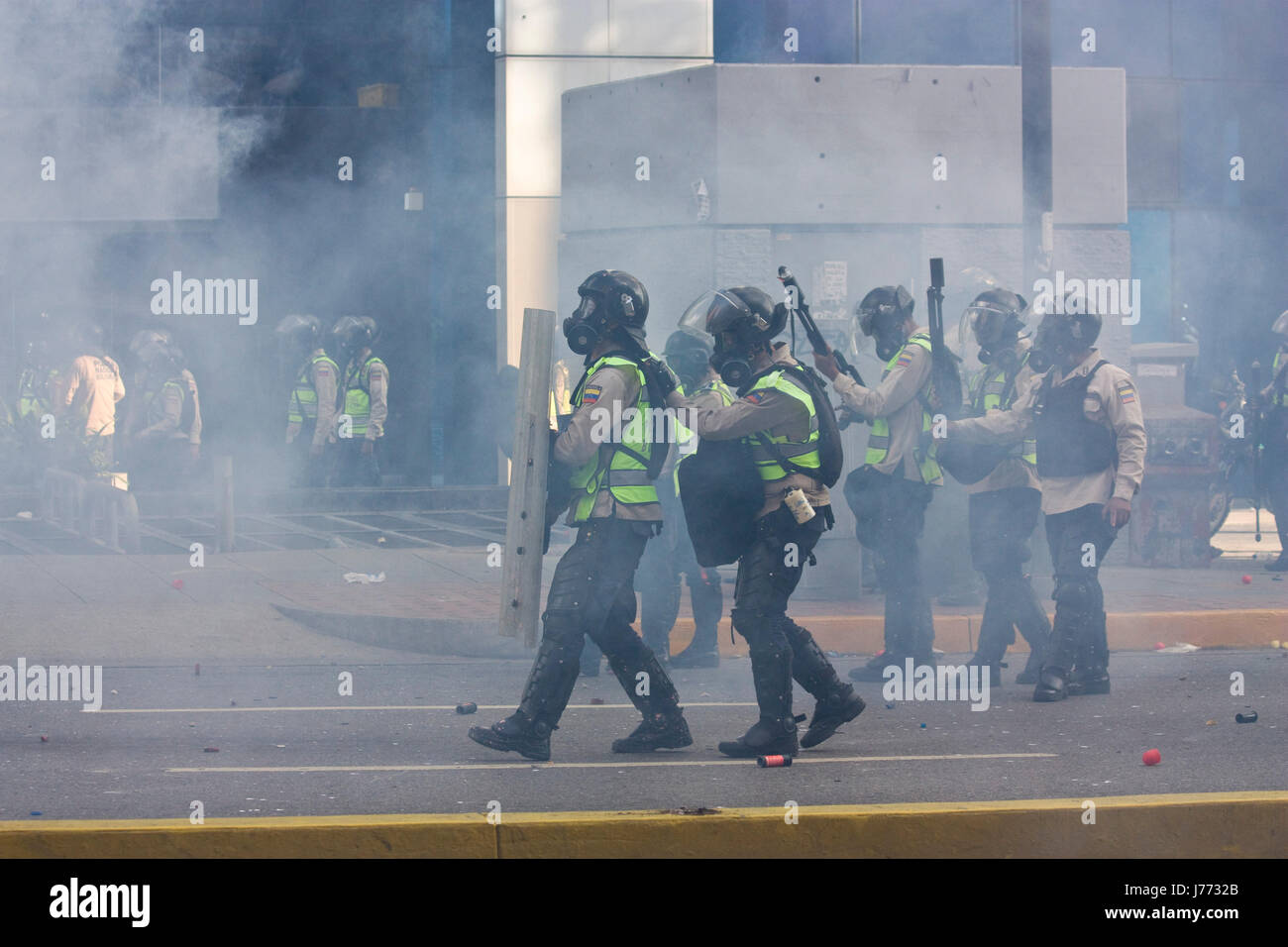 Police officers use tear gas a rubber pellets against demonstrators during a protest against the government of Nicolas Maduro in Caracas. Stock Photo