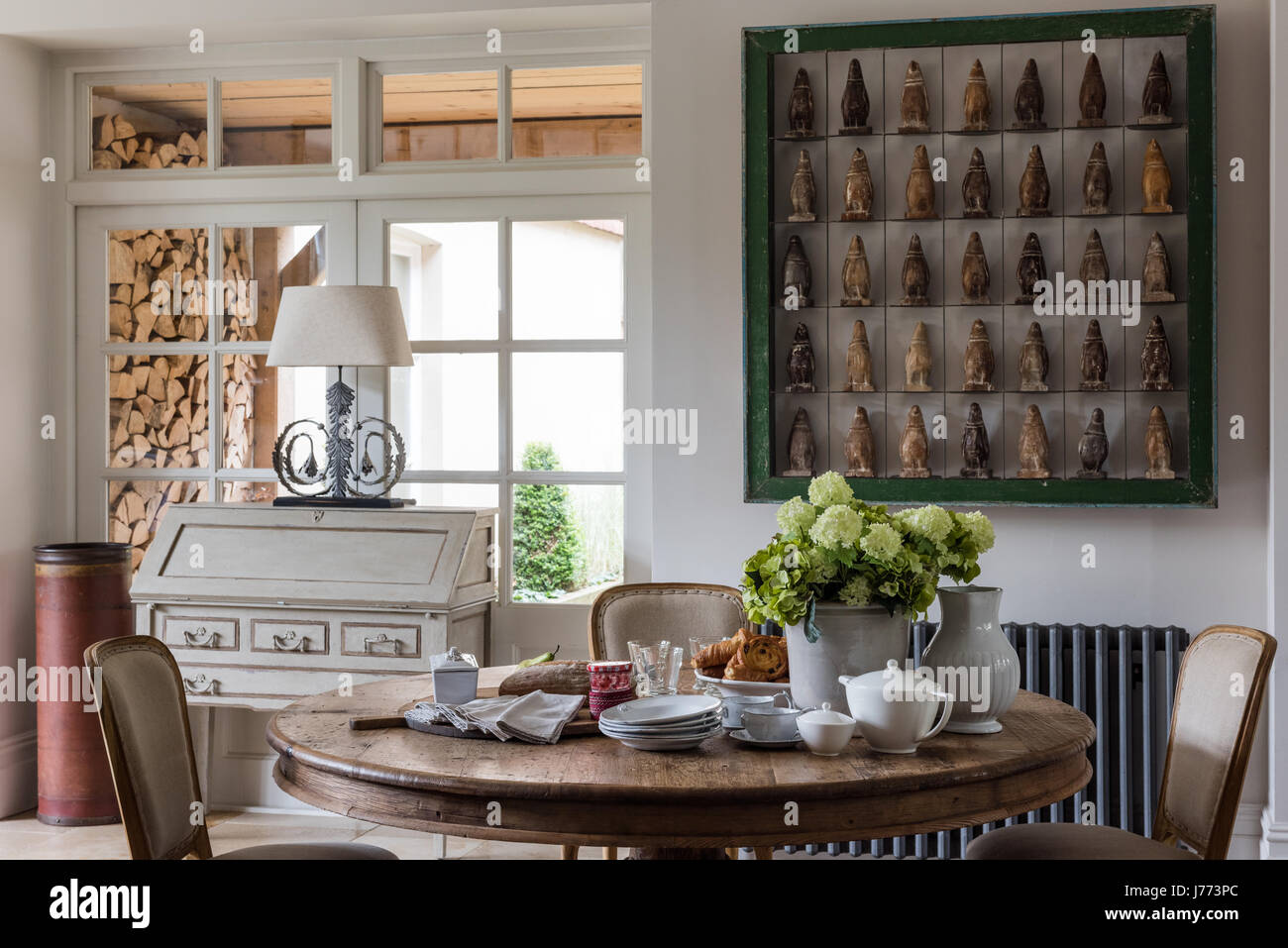 Penguin firgurines displayed in a bold green frame on wall of kitchen. The bureau, the lamp and the circular table are all by Bardoe & Appel Stock Photo