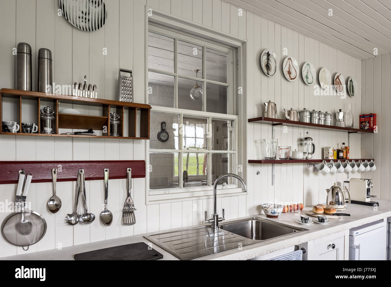 Kitchenware on shelves with stainless steel sink in 17th century Kintyre stone cottage Stock Photo