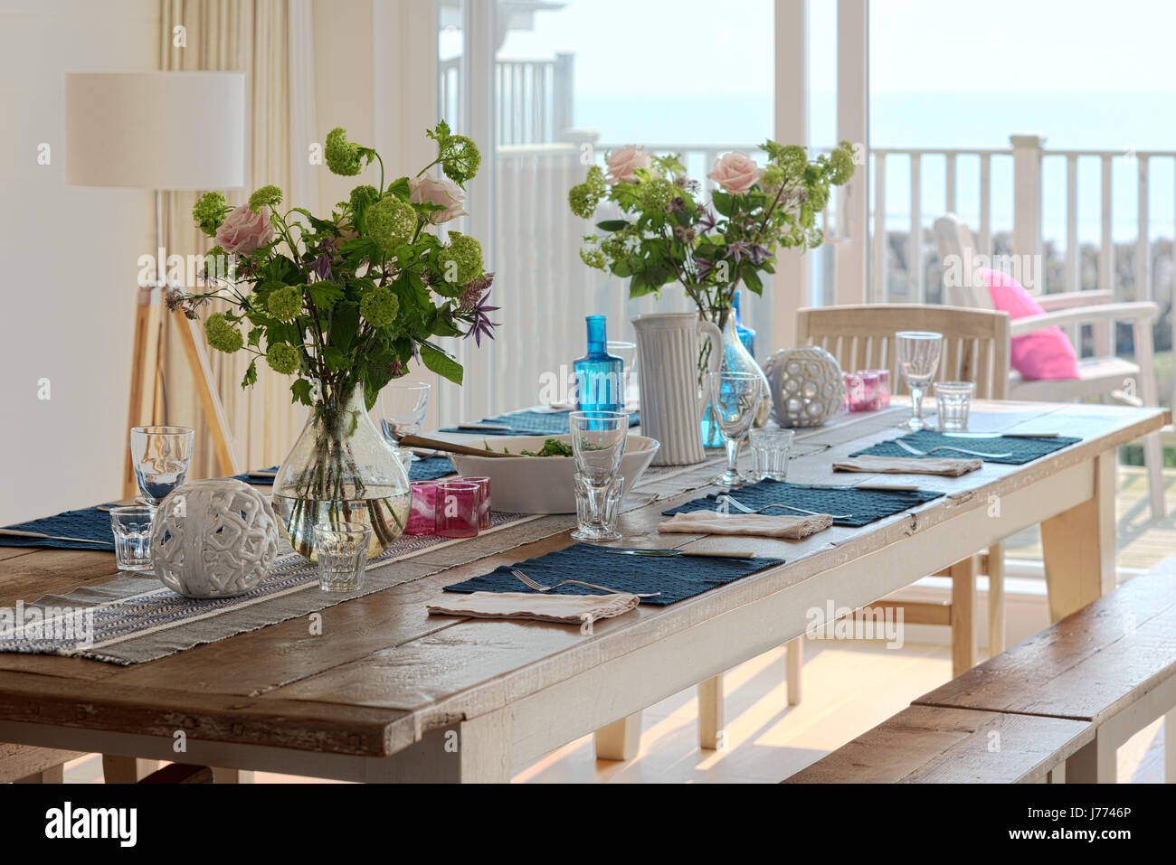 Lunch laid on wooden farm house table in kitchen diner with balcony views out to the sea Stock Photo