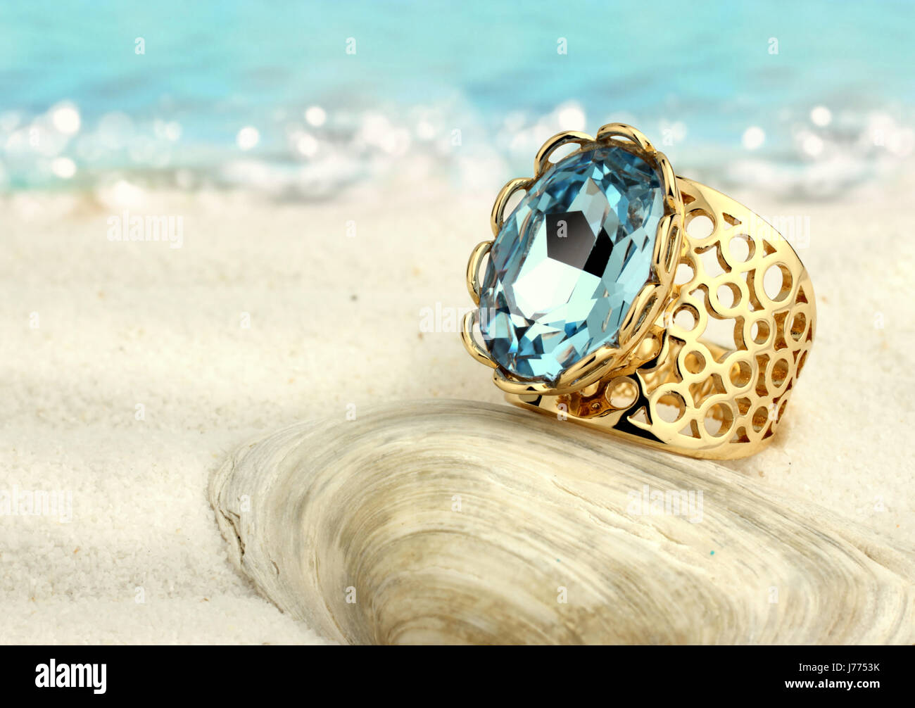 Golden ring with aquamarine on summer sand beach Stock Photo