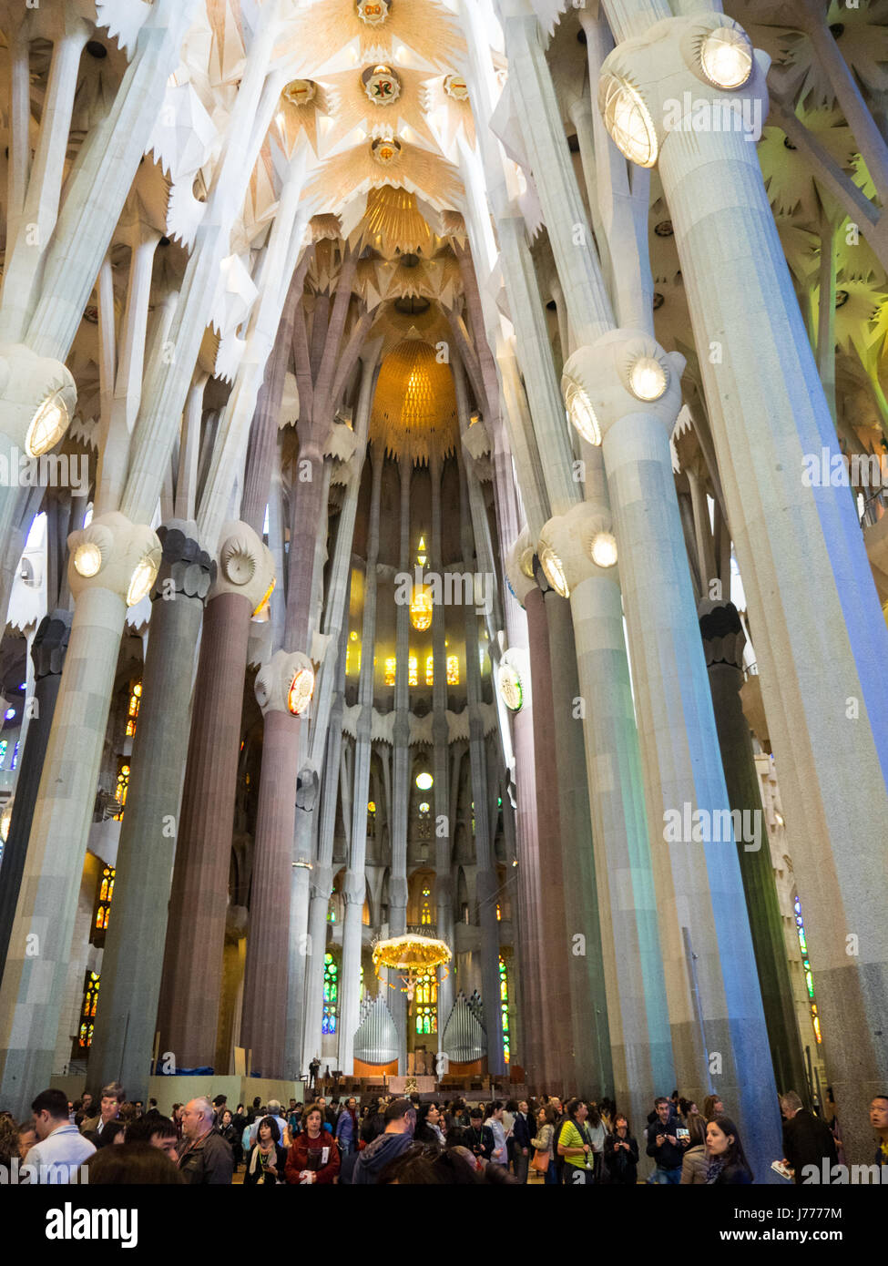 Church congregation and tourists under elaborate and decorative tree like columns and ceiling in Gaudi's Sagrada Familia Basilica, Barcelona, Spain. Stock Photo