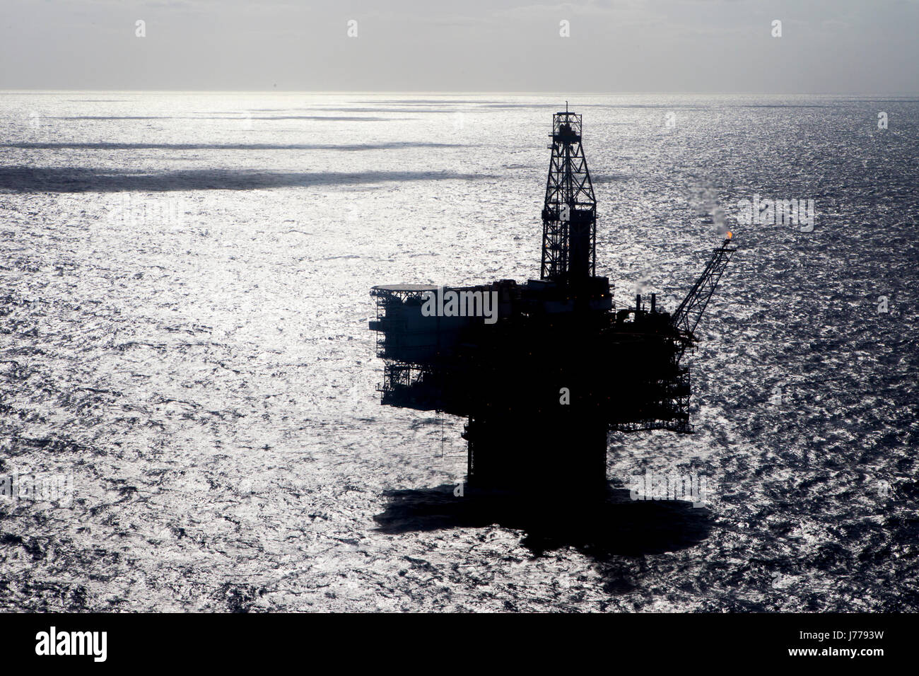 Silhouette oil platform in sea on sunny day Stock Photo