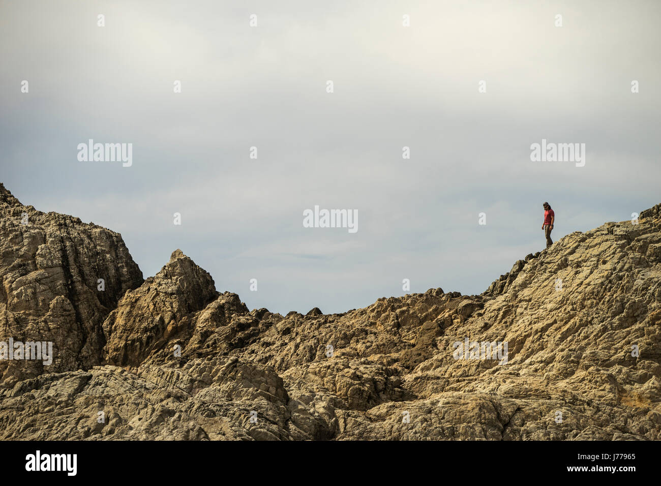 Mid distance view of man walking on mountain against sky Stock Photo