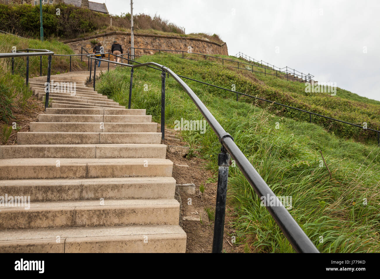 A couple climb the steep step s from the beach to the cliff top at Saltburn by the Sea,England,UK Stock Photo