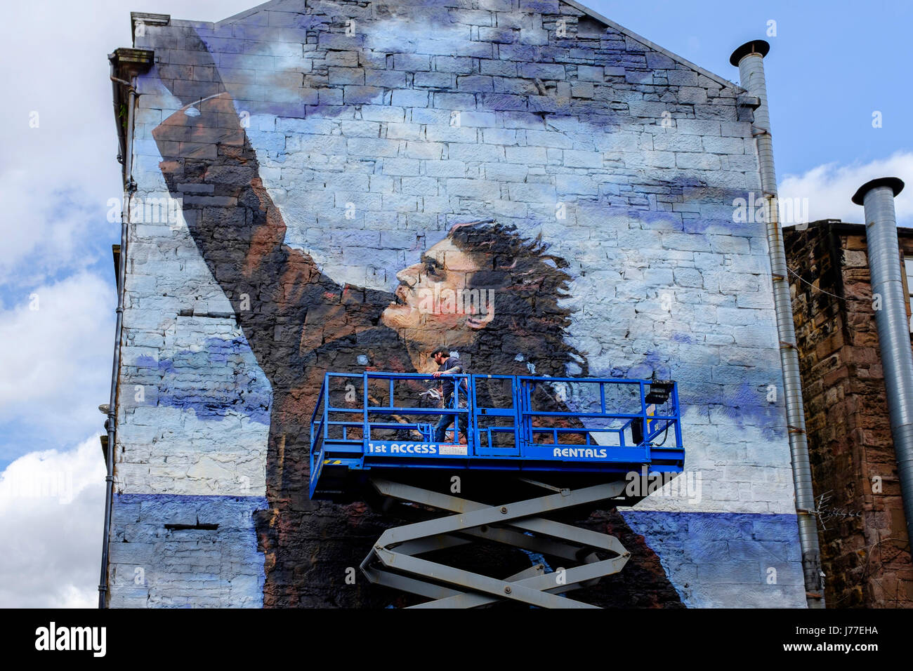 Glasgow, UK. 23rd May, 2017. "Bob" the anonymous street artist, is putting the finishing touches to a 50 foot street mural of Billy Connolly, one of three, as part of Glasgow City's celebration of the world famous comedian's 75th birthday later this year. Billy is also being honoured by a tribute of portraits by Scottish artists John Byrne, Jack Vettriano and Racheal MacLean exhibiting in The Peoples Palace Museum in Glasgow Credit: Findlay/Alamy Live News Stock Photo