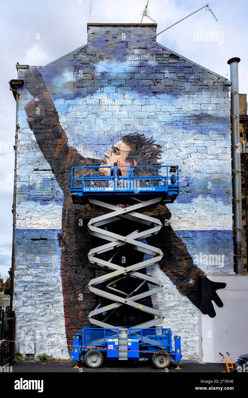 Glasgow, UK. 23rd May, 2017. "Bob" the anonymous street artist, is putting the finishing touches to a 50 foot street mural of Billy Connolly, one of three, as part of Glasgow City's celebration of the world famous comedian's 75th birthday later this year. Billy is also being honoured by a tribute of portraits by Scottish artists John Byrne, Jack Vettriano and Racheal MacLean exhibiting in The Peoples Palace Museum in Glasgow Credit: Findlay/Alamy Live News Stock Photo