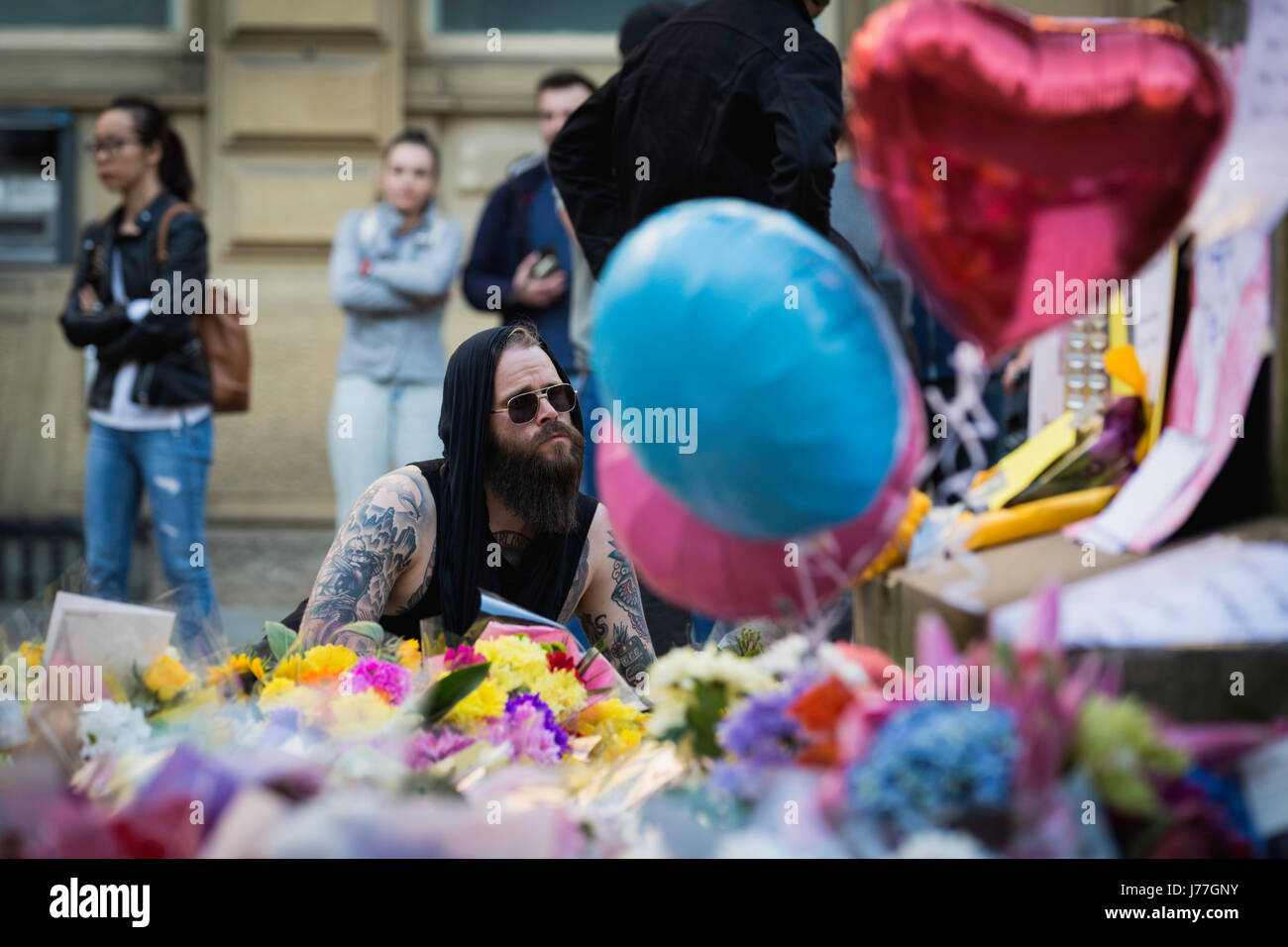 Manchester, UK. 23rd May, 2017. A man leaves flowers at St Anns Square, Manchester after a vigil was held in solidarity after an attack on Manchester Arena the night before which claimed 22 lives and injured 59. Credit: Andy Barton/Alamy Live News Stock Photo