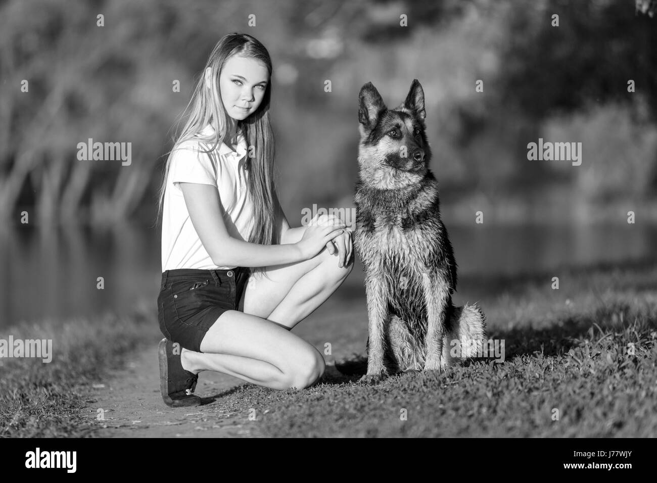 Teenage girl in white shirt with her german shepherd sitting on pathway ...