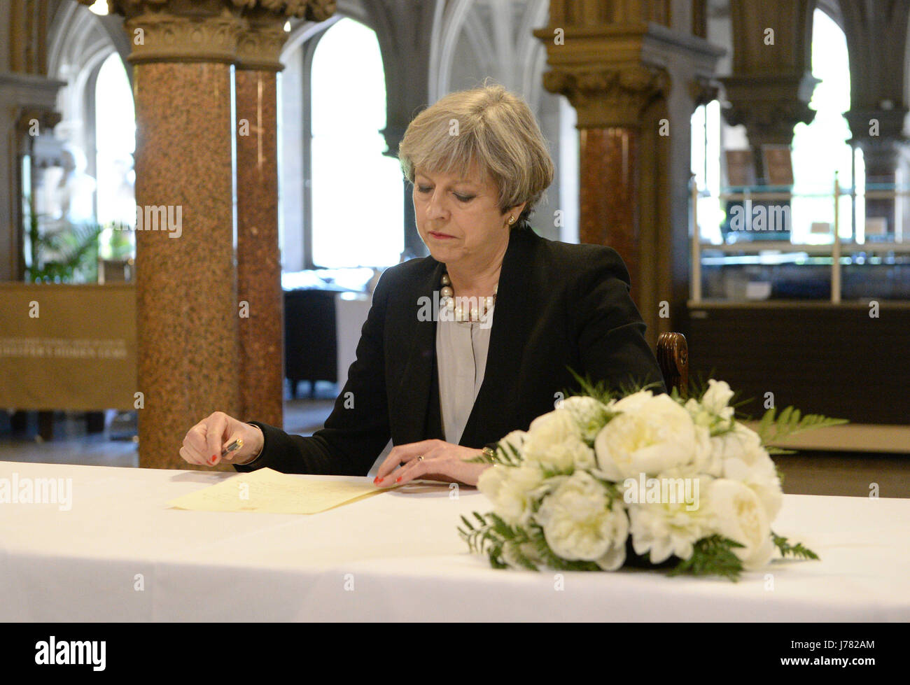Prime Minister Theresa May writes a message at Manchester Town Hall in Manchester after a 23-year-old man was arrested in connection with the Manchester concert bomb attack. Stock Photo