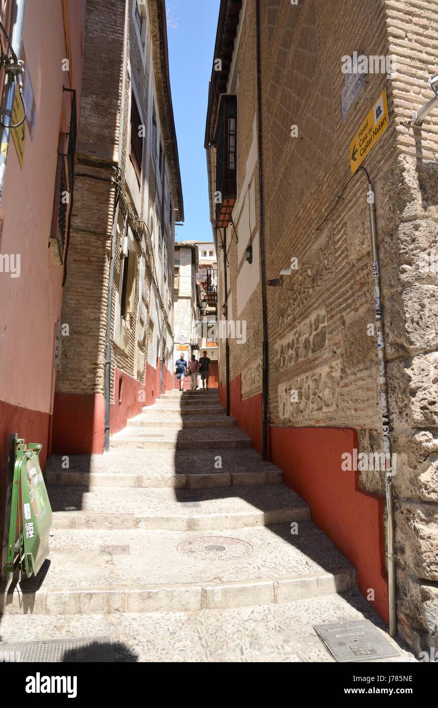 People descending by a narrow street in slope in the quarter of  Albayzin  that leads to the Darro way in Granada, Andalusia, Spain. Stock Photo