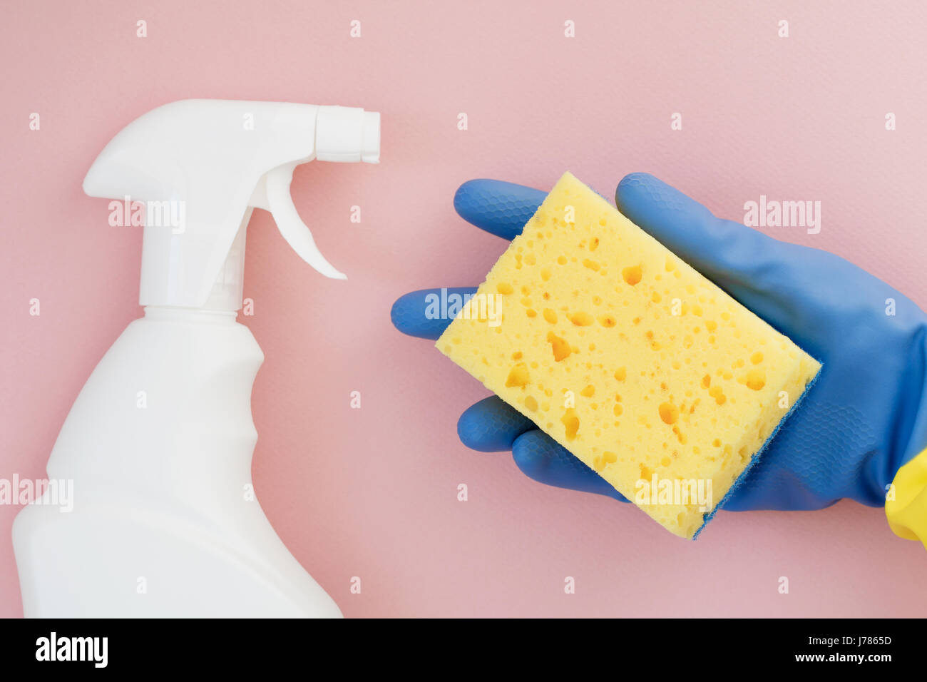 Hand in a blue rubber glove holds a yellow sponge for cleaning on a ...