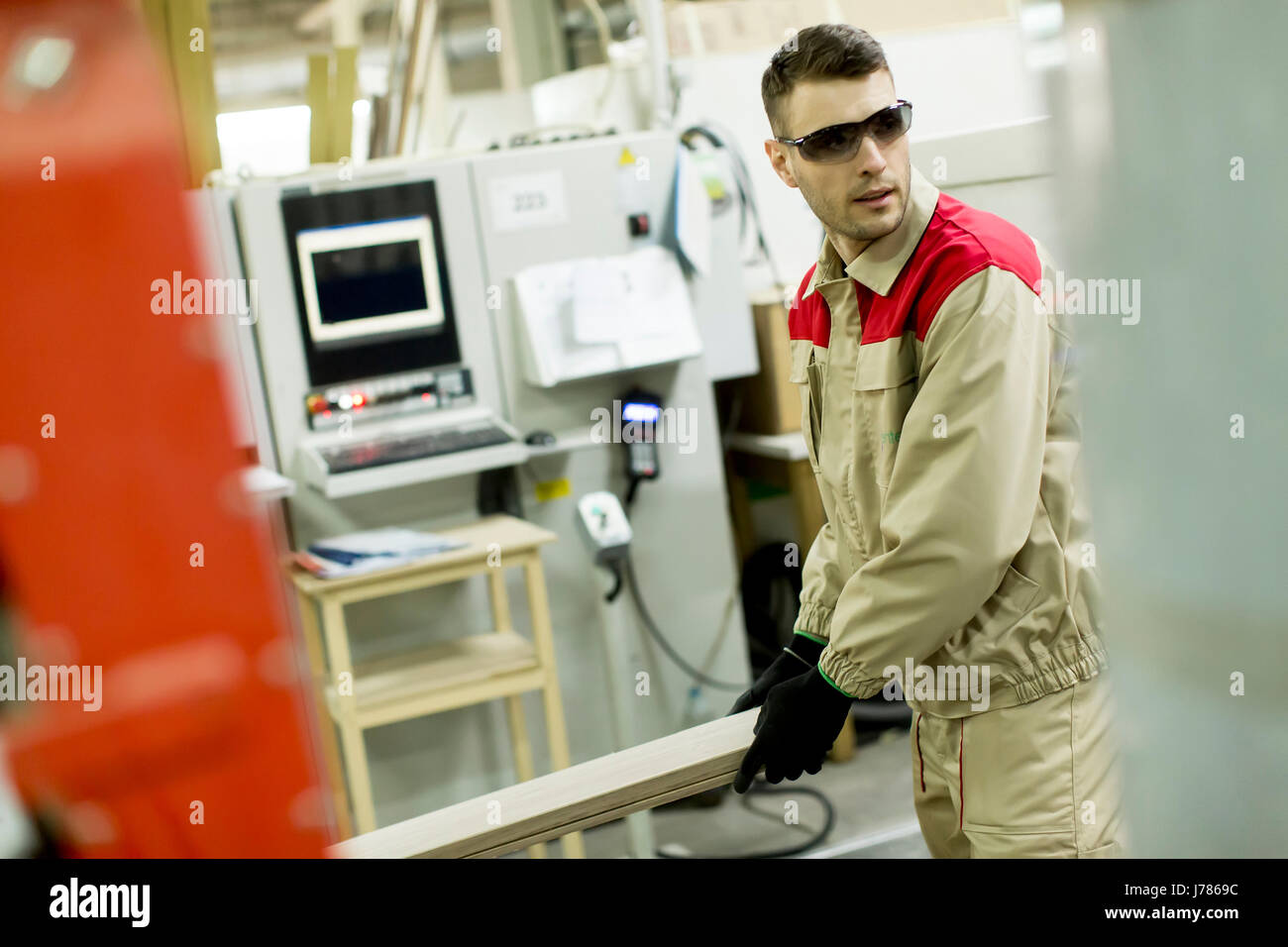 Craftsman wearing working clothes and protective eyewear woodworking in