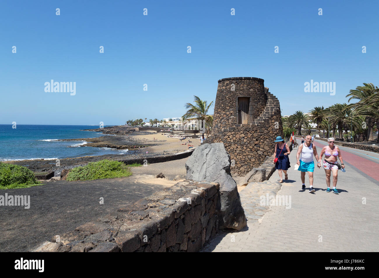 Tourists walking beside the sea, Playa Bastian, Costa Teguise, Lanzarite Canary Islands Europe Stock Photo