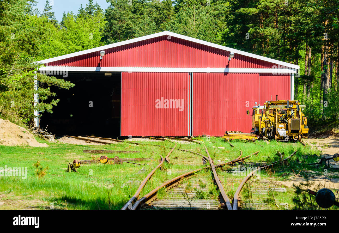 Brosarp, Sweden - May 18, 2017: Documentary of public historic railway station area. Open red storage building with yellow vintage maintenance vehicle Stock Photo