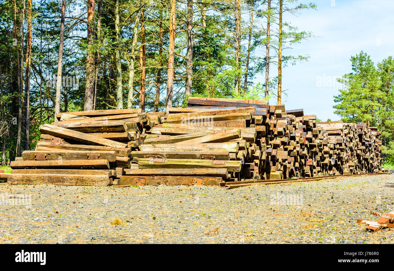Large stack of used railway ties on storage area in woodland environment. Stock Photo