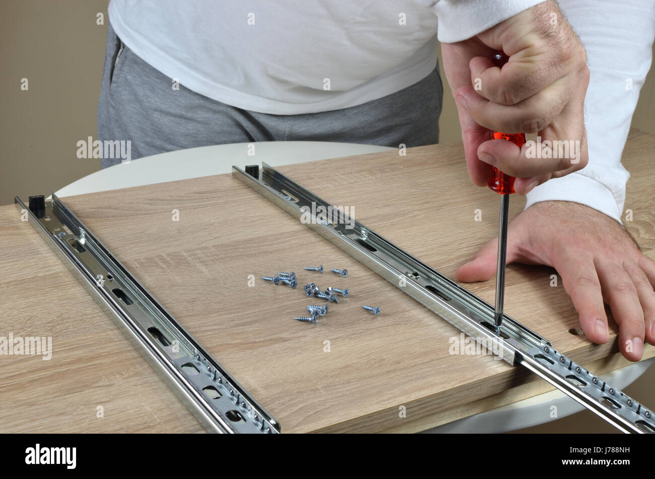 Man holding a screwdriver and installing drawer slides on an element of
