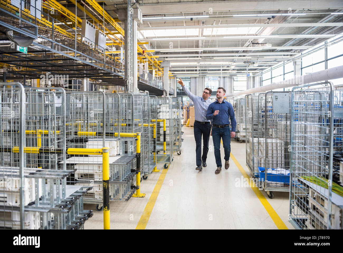 Two men walking and talking in factory shop floor Stock Photo - Alamy