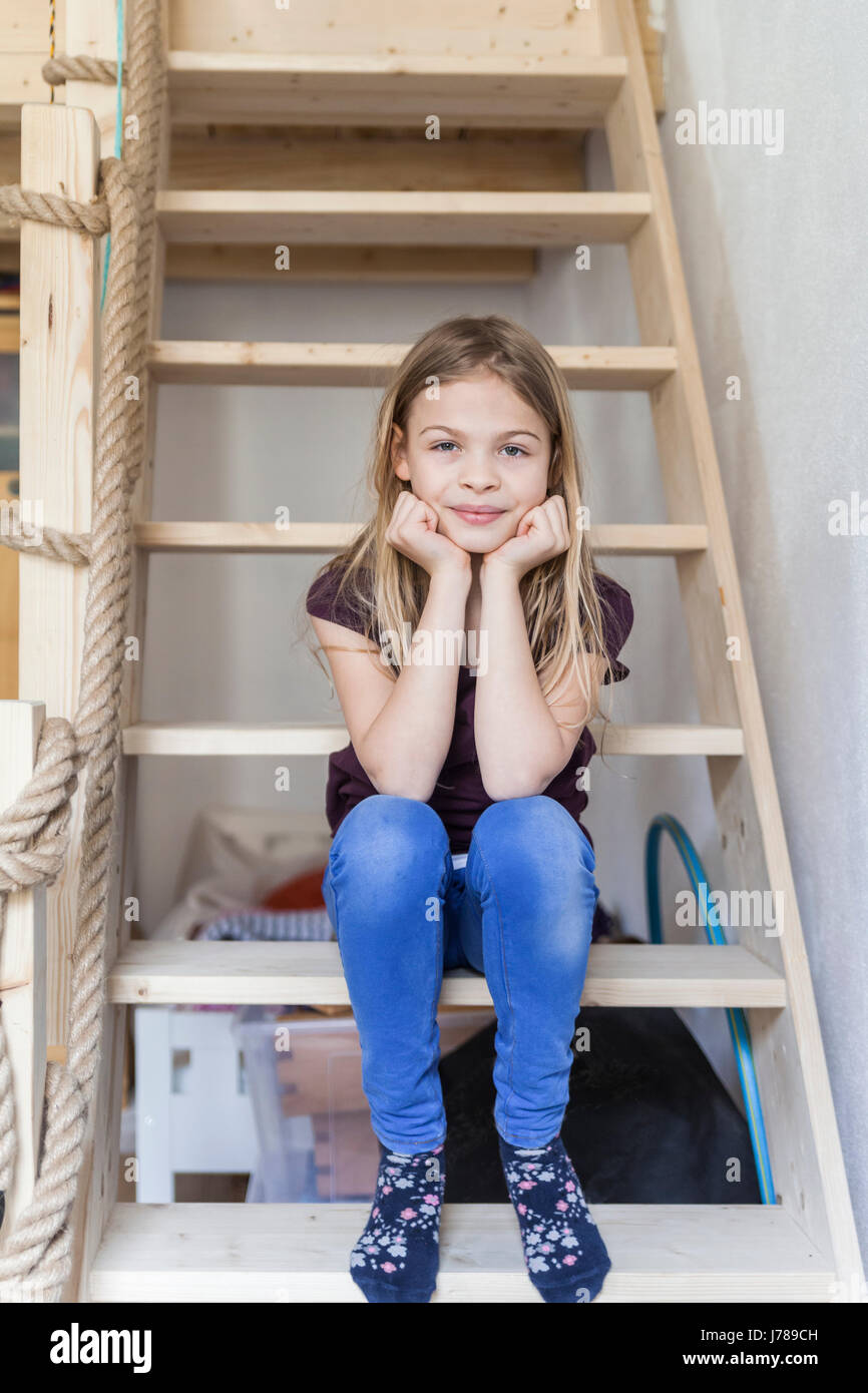 Portrait of girl sitting on ladder of her loft bed Stock Photo